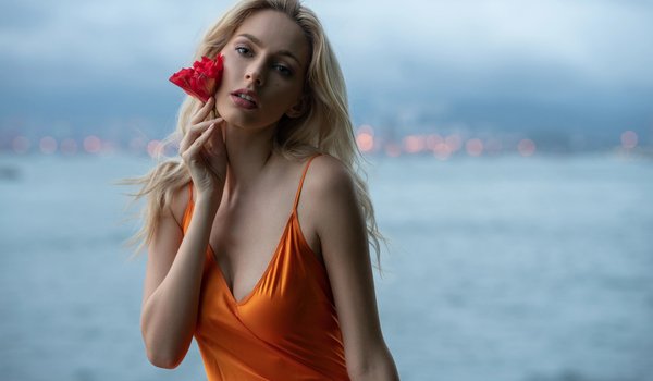 Обои на рабочий стол: bare shoulders, blonde, blue eyes, bokeh, breast, chest, cleavage, depth of field, dress, flower, girl, looking at camera, looking at viewer, model, mouth, open mouth, orange dress, photo, portrait, sea, strap, wavy hair