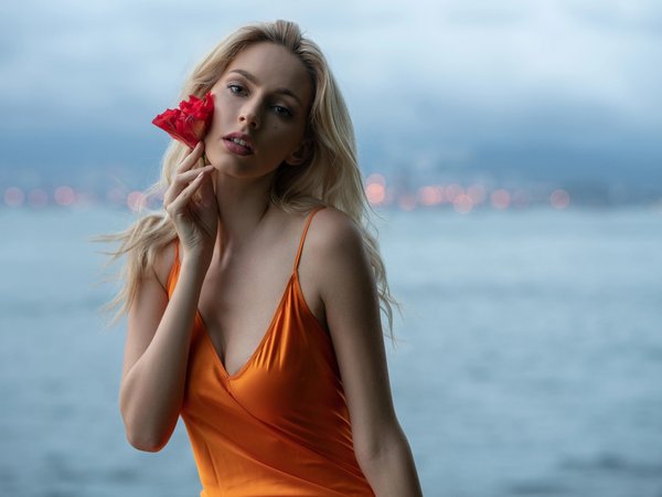 bare shoulders, blonde, blue eyes, bokeh, breast, chest, cleavage, depth of field, dress, flower, girl, looking at camera, looking at viewer, model, mouth, open mouth, orange dress, photo, portrait, sea, strap, wavy hair