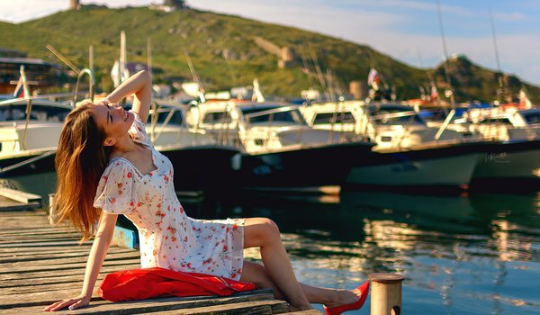 Обои на рабочий стол: bay, boat, brunette, clouds, dress, heeled shoes, hill, jacket, model, nature, red jacket, red shoes, sitting, sky, smiling, white dress, women, women outdoors